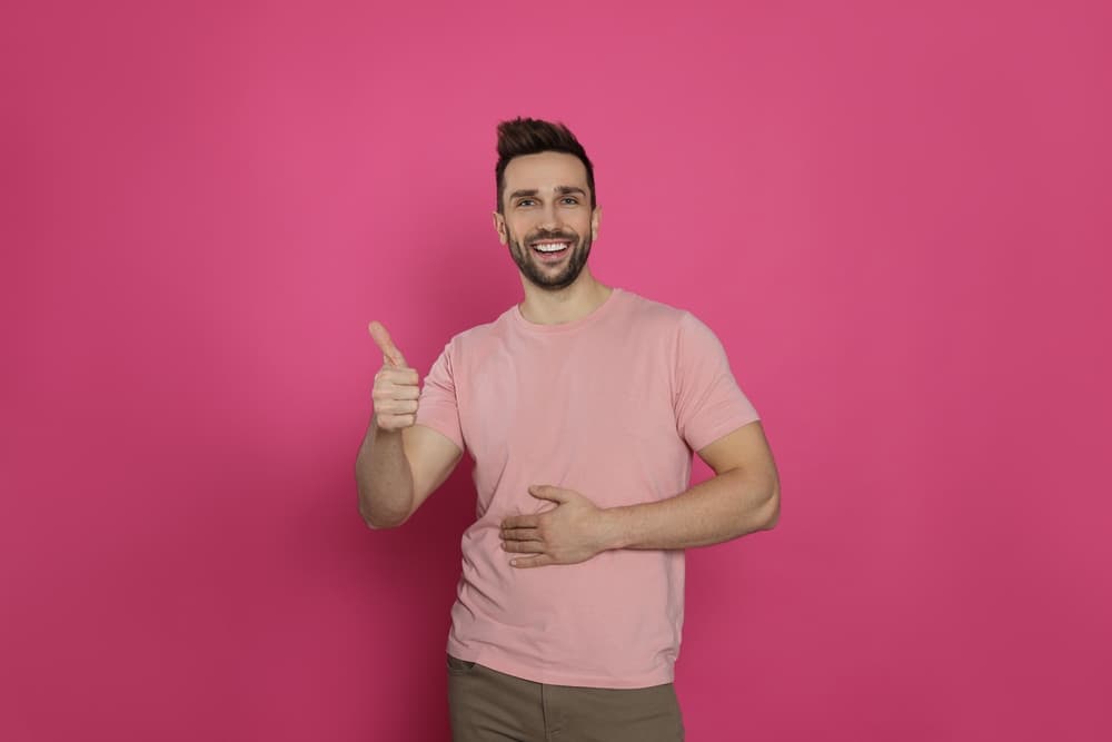 Homme souriant pouce levé sur fond rose
