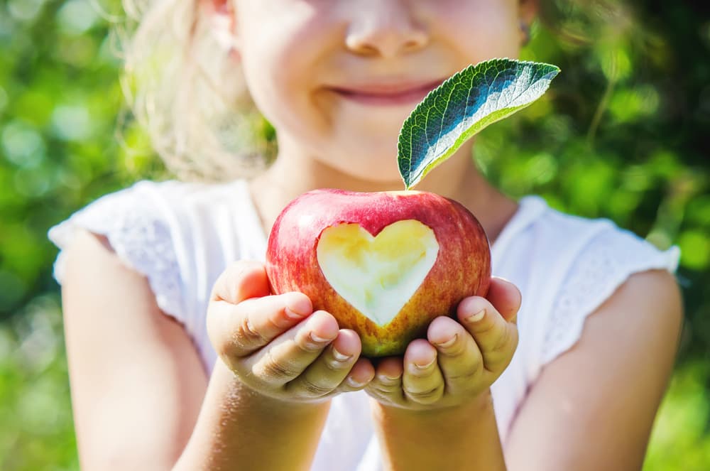 Enfant tenant une pomme creusée en forme de cœur
