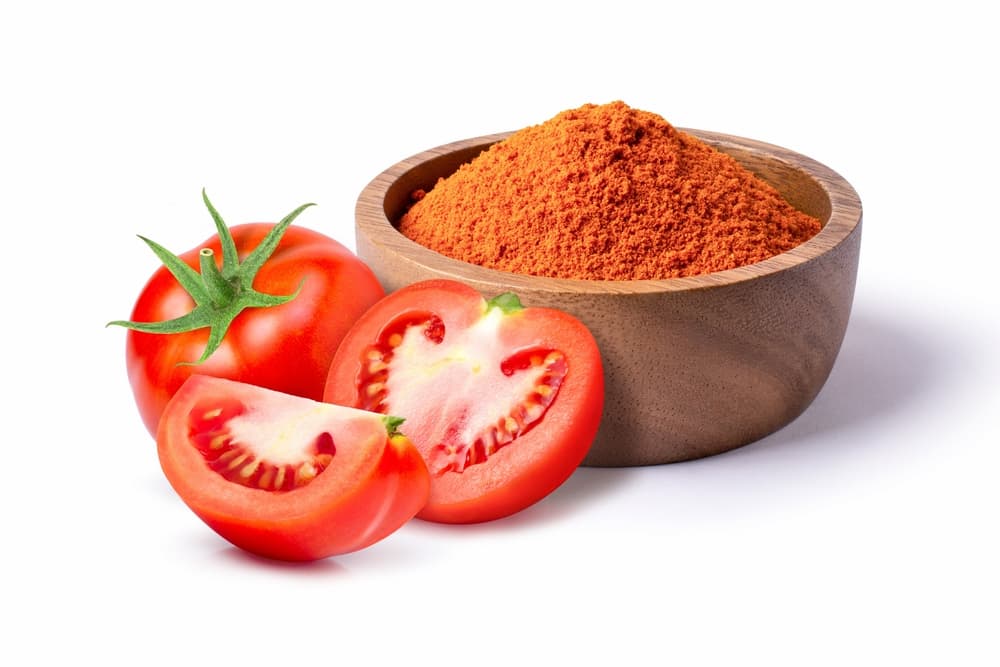 Tomates fraîches et poudre de tomate dans un bol en bois