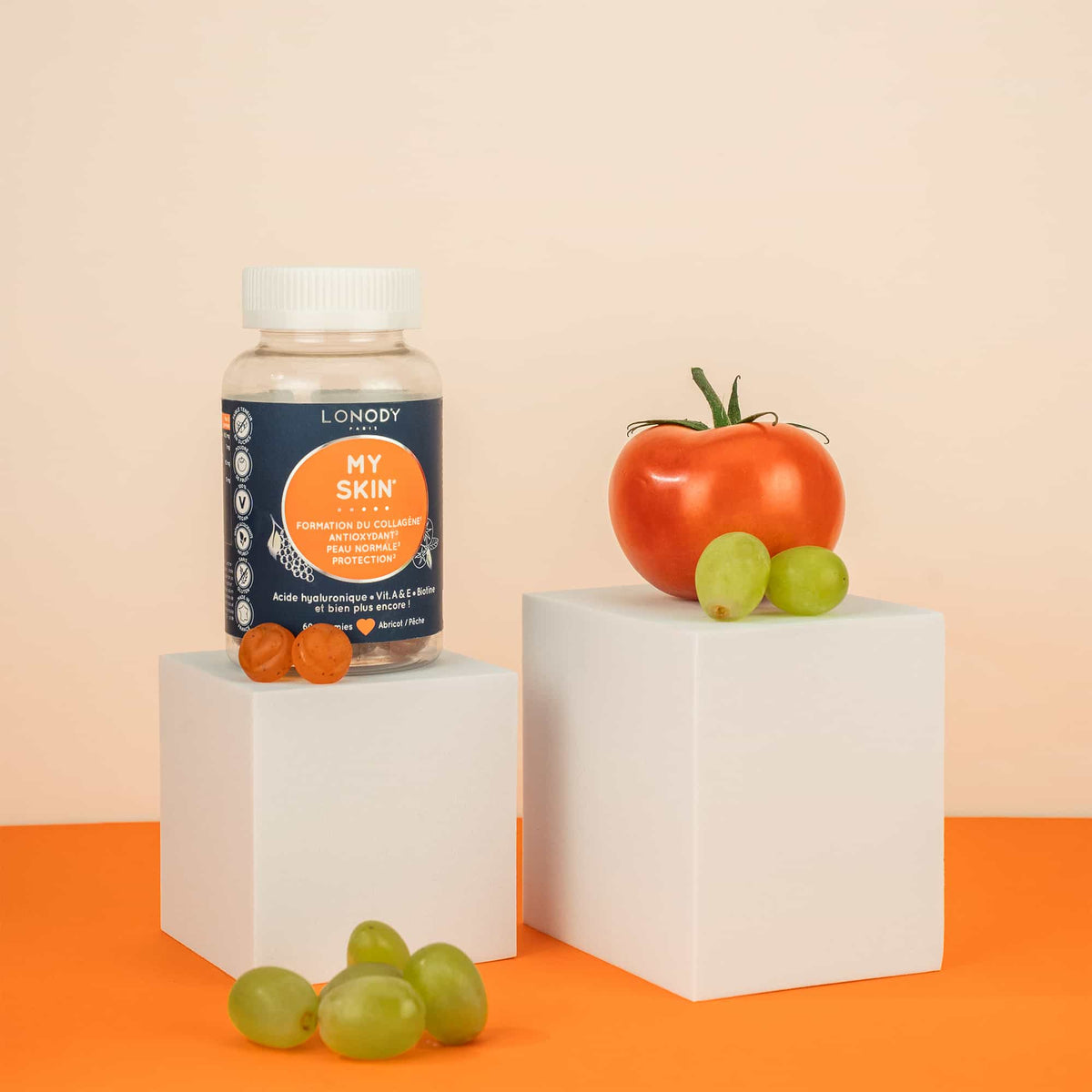 Flacon My Skin de Lonody avec ses gummies et des tomates sur fond orange